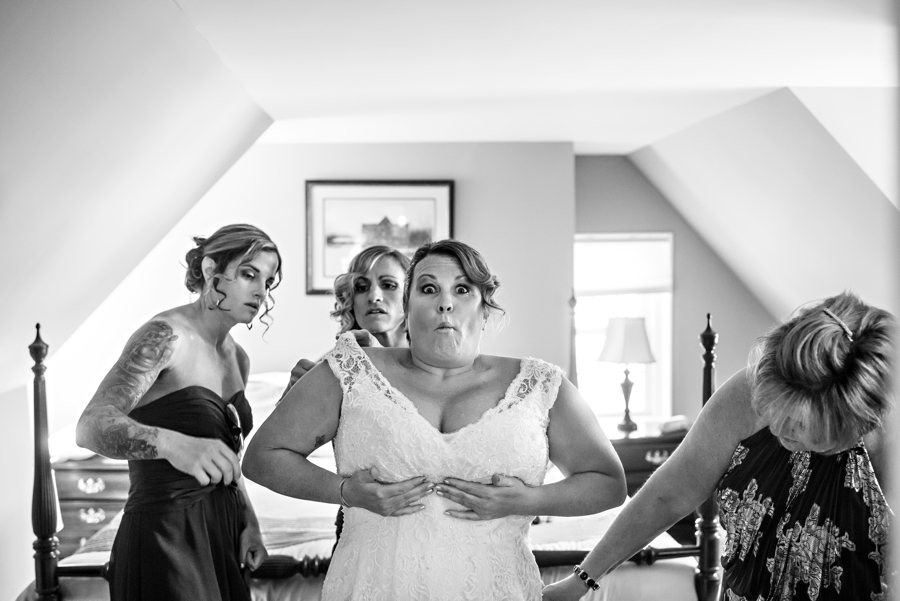 A funny picture of a bride getting into her wedding dress with her bridesmaids.